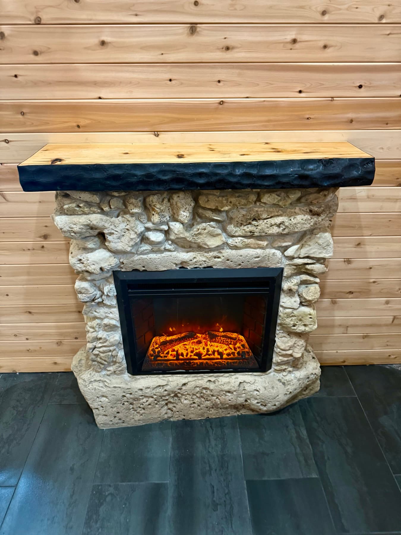 A fieldstone fireplace with a hand-hewn timber mantel