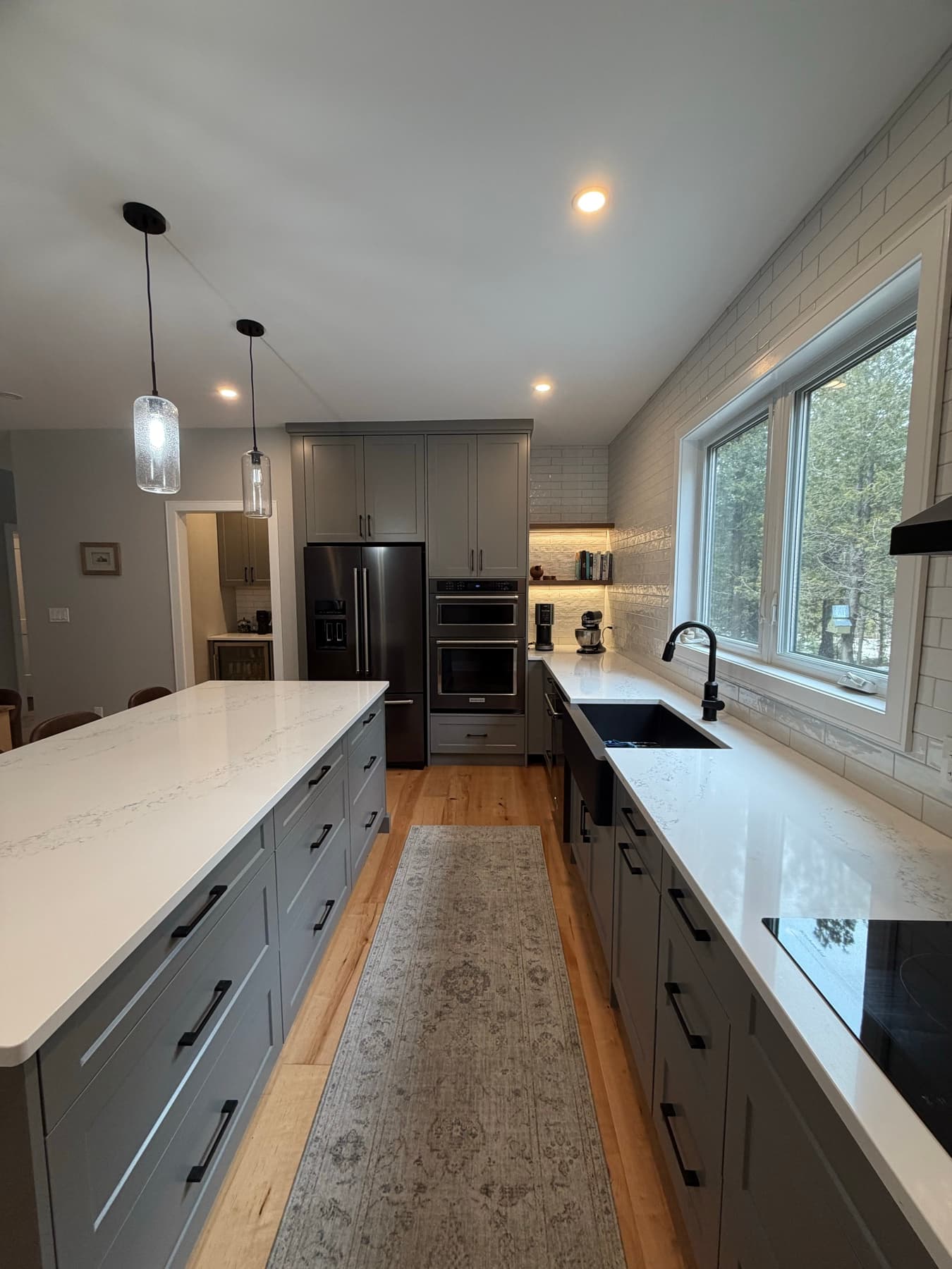 Dark grey shaker kitchen with a white quartz island, pendant lights and an apron sink